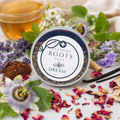 A round tin of Southern Roots Spice 'Dream' spice blend, styled on a white surface with tea, lavender, passion flowers, rose petals, and vanilla beans.